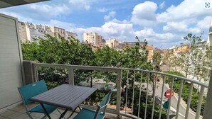 A balcony with a table and chairs, overlooking a cityscape with buildings and trees. - The Dunes of Blossac 100m from the beach (Les Sables-d´Olonne)