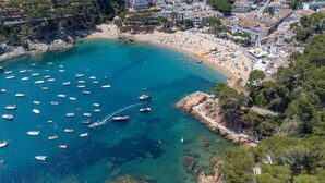 Vista aérea de un pueblo costero con playa, barcos y edificios residenciales.