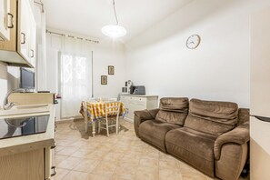 A compact living space with a kitchenette, a dining area, and a reclining sofa.
