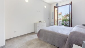 Une chambre à coucher comprenant un lit, une commode, un miroir et une porte donnant sur un balcon.