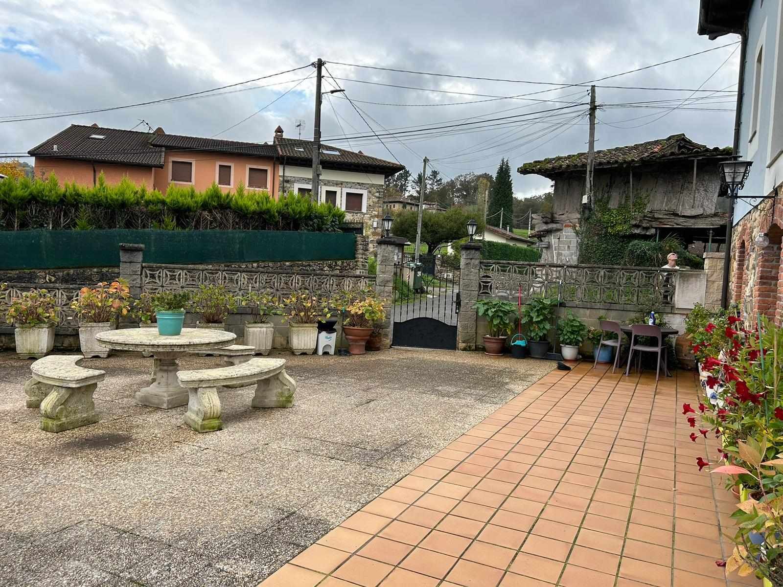 A courtyard with a stone table and chairs, surrounded by potted plants and a tiled floor.