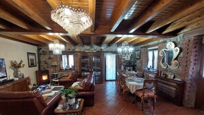 Ein geräumiges Wohnzimmer mit Kamin, Ledersofas, einem Essbereich und einer Kristallleuchtre.'