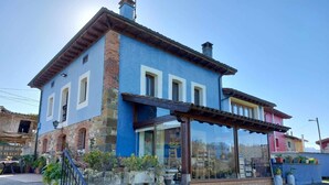 Ein zweistöckiges Haus mit blauer Fassade, Steinsockel und einer Veranda.