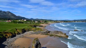 Eine Küstenlandschaft mit Strand, felsigem Ufer und Bergen in der Ferne.