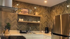 A modern kitchen with white cabinets, a stainless steel refrigerator, and a herringbone-patterned backsplash. - Comfortable1 bedroom suite located in Cowichan Valley close to various wineries. (Cobble Hill)
