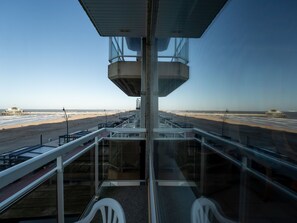 Ein Kontrollturm mit freiem Blick auf den Strand und den Flughafen im Hintergrund.