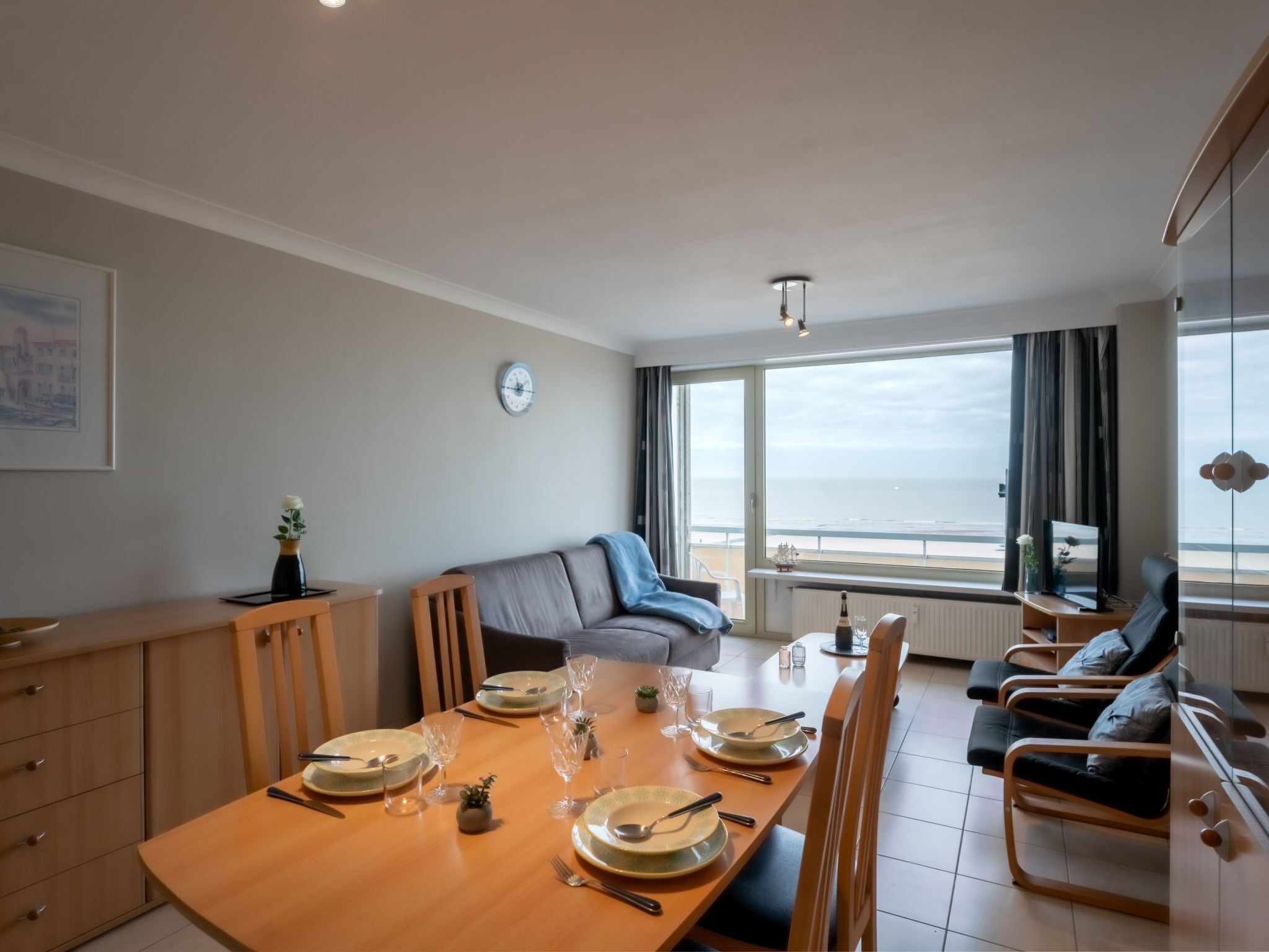 Ein Essbereich mit Tisch für vier Personen, einer Couch und Blick aufs Meer.