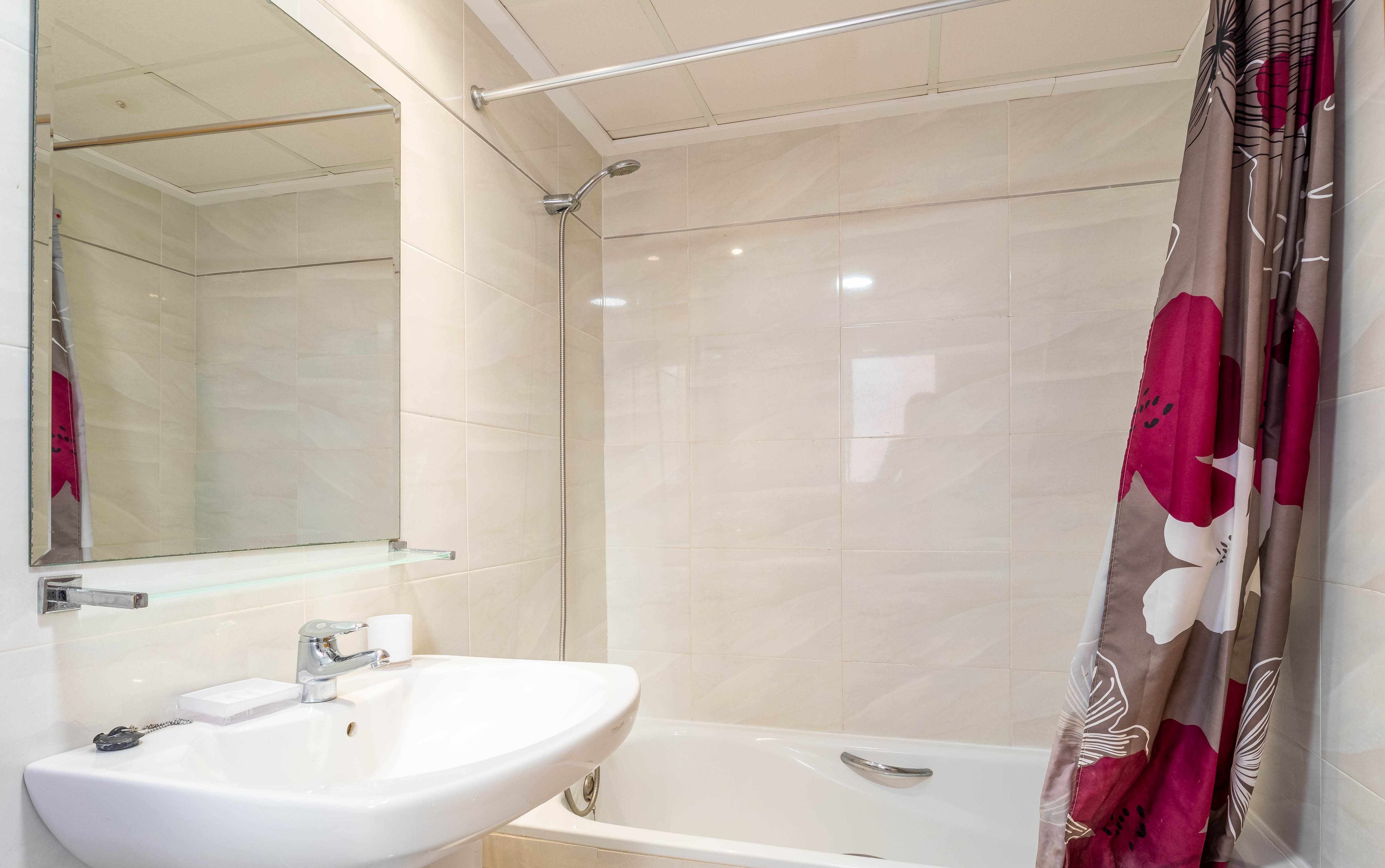 A bathroom with a white sink, a bathtub, and a shower.