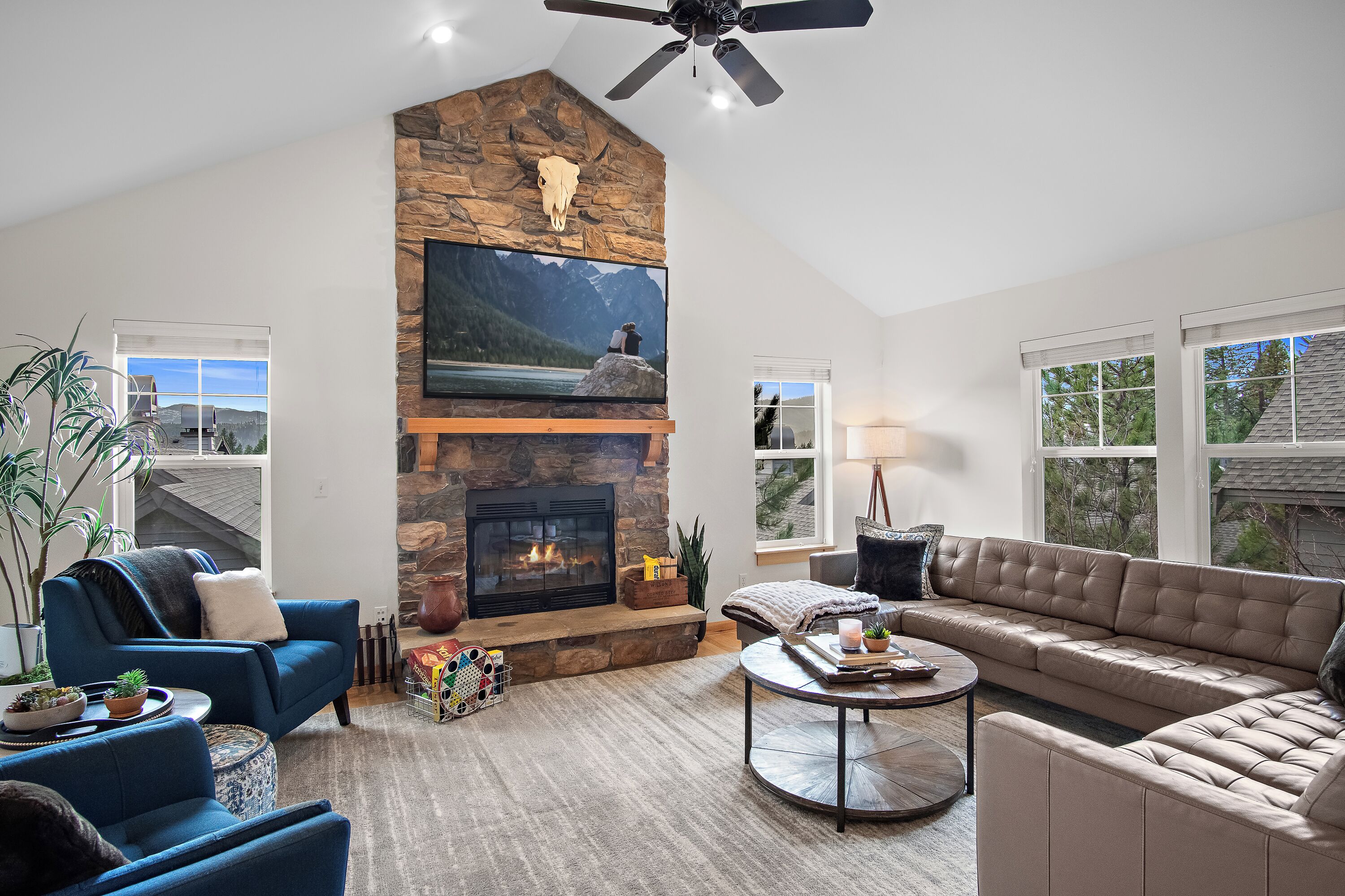 A modern living room with a stone fireplace, a large TV mounted above it, and comfortable seating.