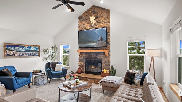 A spacious living room with a stone fireplace, comfortable seating, and a large TV.
