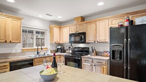A modern kitchen with wooden cabinets, a black refrigerator, a microwave, and a coffee maker.