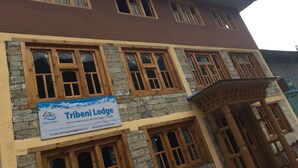 A multi-story building with wooden window frames and a sign for Tribeni Lodge. - Tribeni Lodge Restaurant And Bar (Phakding)