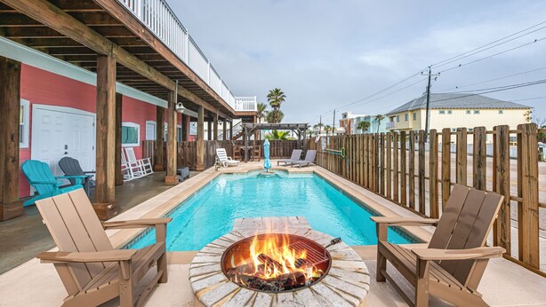 An outdoor pool area with Adirondack chairs, a fire pit, and a covered deck. - Corral Cottage- Private Pool Oasis, Games, Pets, Golf Cart zoned & Walk to Beach (Port Aransas)