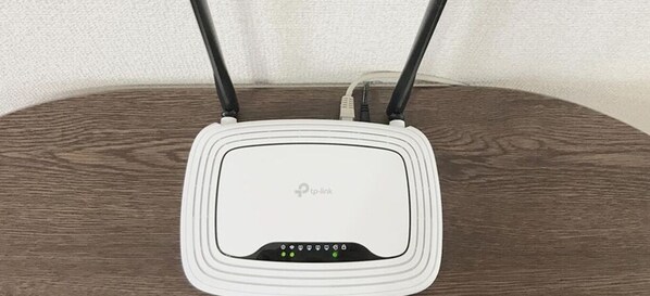 A white router with a logo on the front, placed on a wooden surface. - Best room in Kawagoe (Kawagoe)