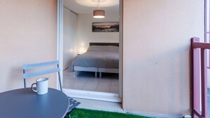 Une chambre à coucher avec un lit, une table de chevet, une lampe et une fenêtre.