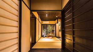 A traditional Japanese interior with tatami flooring, sliding doors, and a view of a garden.