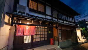 A traditional Japanese building with a wooden entrance and a red banner.