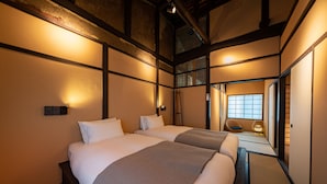 A traditional Japanese-style hotel room with tatami flooring, a shoji screen, and a sliding door leading to a balcony.