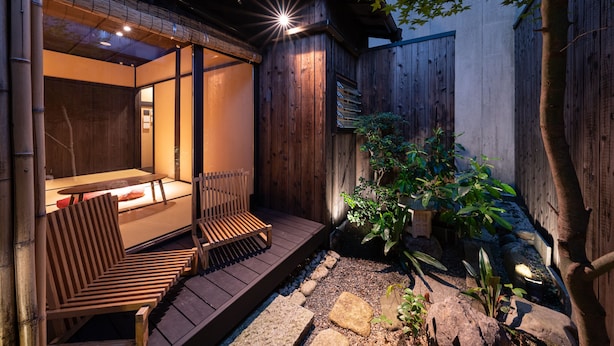 A wooden deck with seating and a small table, surrounded by a wooden fence and plants.