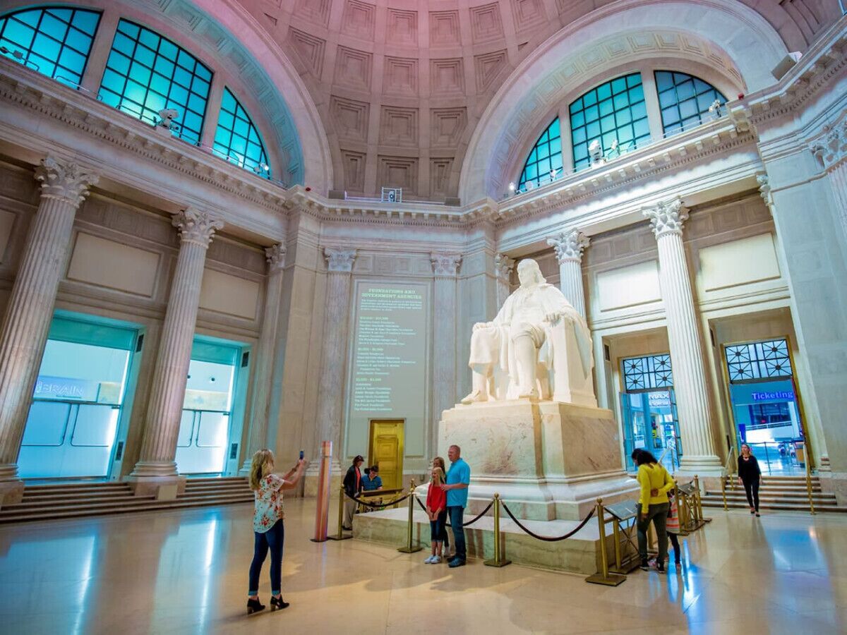 A grand interior with a large statue, high ceilings, and classical architecture.