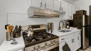 A modern kitchen with white cabinetry, stainless steel appliances, and a white countertop. - Charming 2BR Philadelphia Stay, Prime Location + Parking (Philadelphia)