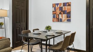 A dining area with a marble table, four chairs, and a modern abstract painting on the wall. - Charming 2BR Philadelphia Stay, Prime Location + Parking (Philadelphia)