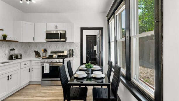 A modern kitchen with white cabinets, a built-in oven, and a dining area with a table set for four. - Modern 3BR Philadelphia Stay, Central Location & Free Parking (Philadelphia)