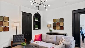 A modern living room with a grey sofa, a black armchair, a round coffee table, and a black bookshelf. - Modern 3BR Philadelphia Stay, Central Location & Free Parking (Philadelphia)