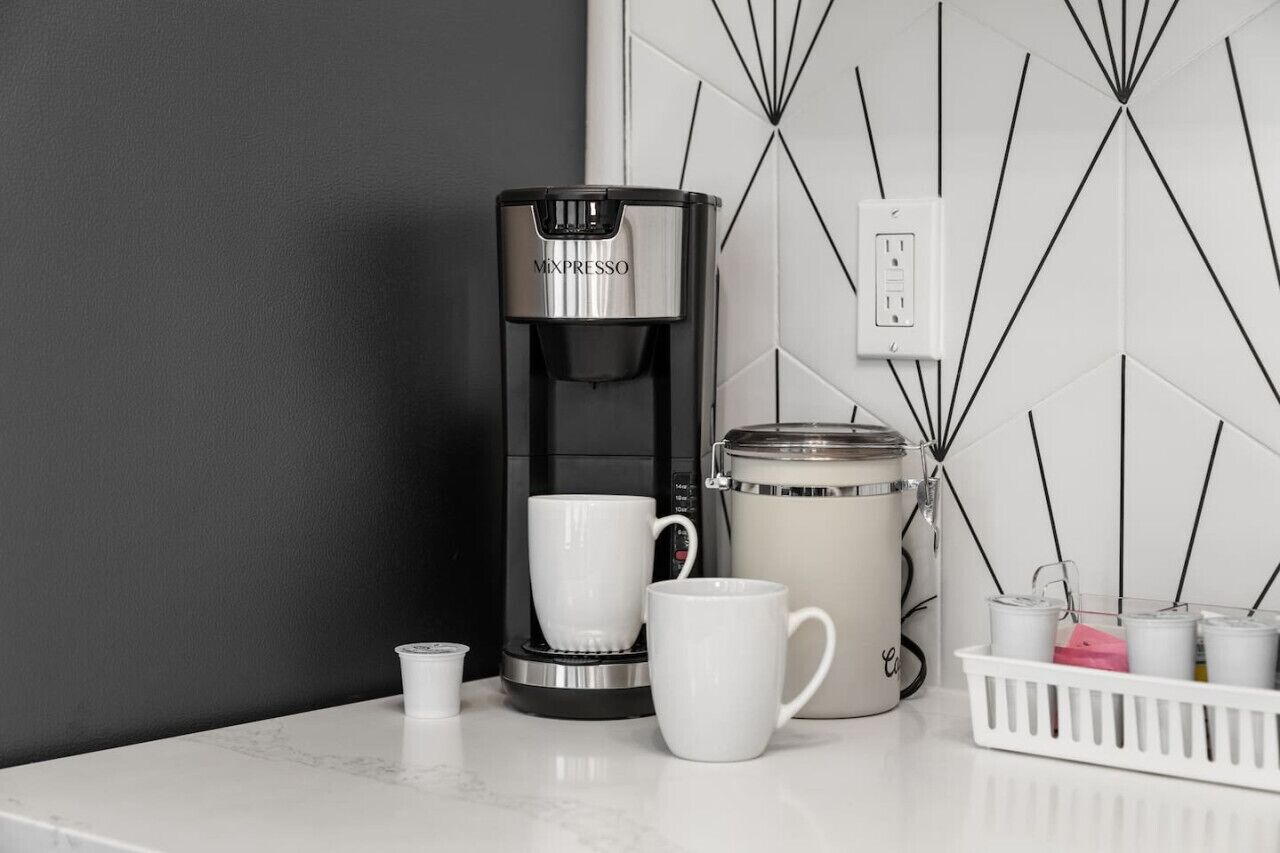 En kaffebryggare, en mugg, en termos och en aromdiffuser står på en bänkskiva.