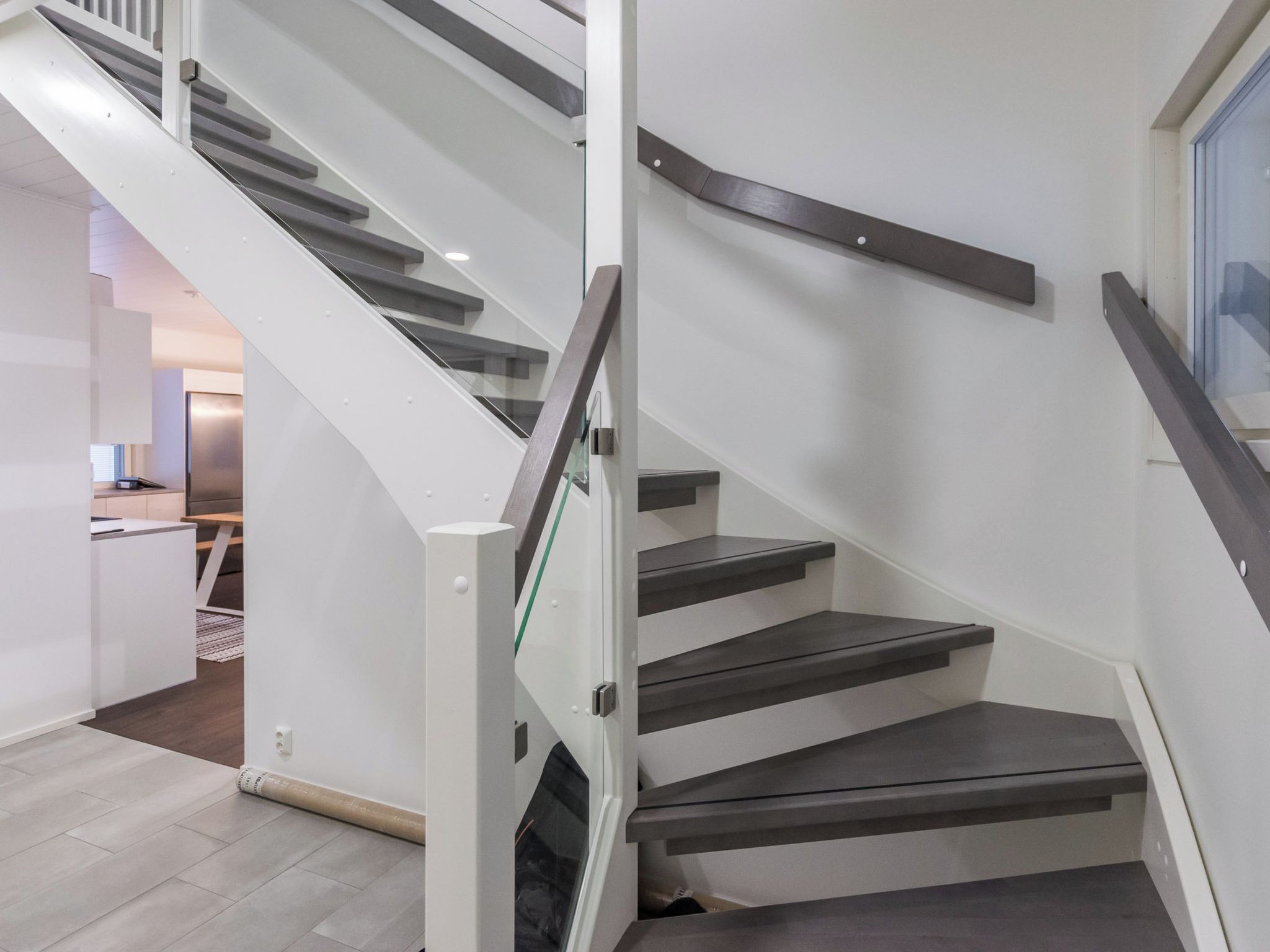 A modern staircase with glass railings and dark steps.