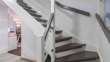 A modern staircase with glass railings and dark steps.