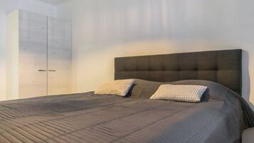 A bedroom with a large bed, two pillows, a wardrobe, and a ceiling light.