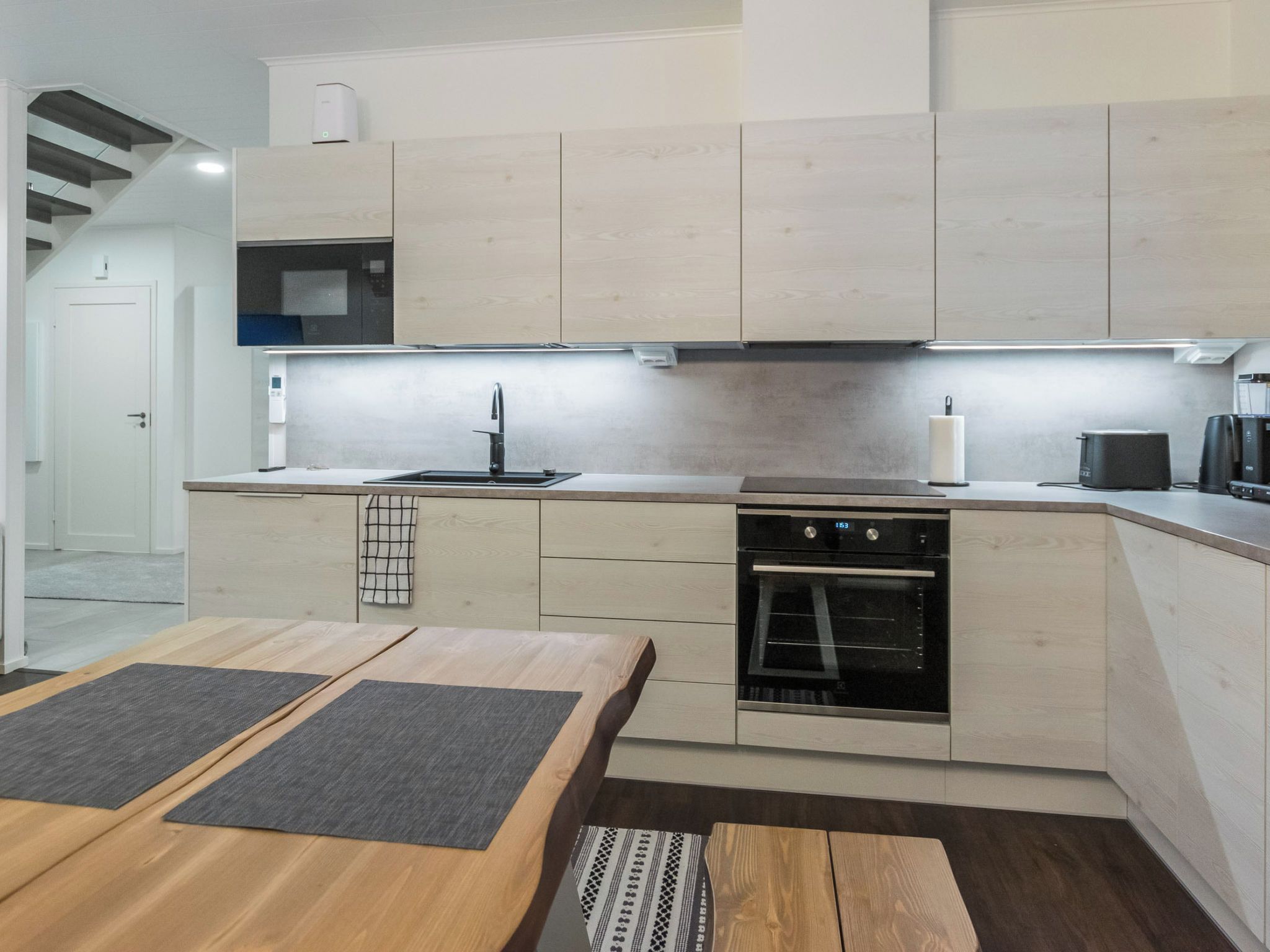 A modern kitchen with a built-in oven, a sink, and a coffee maker.
