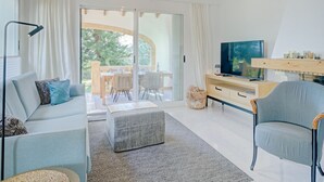 Ein modernes Wohnzimmer mit einer Couch, einem Hocker und einem Fernseher auf einem Holzboden.