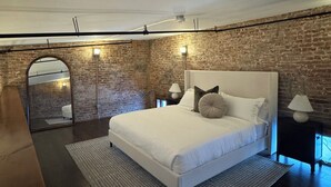 Una camera da letto con un letto grande, un muro in mattoni e un lucernario.