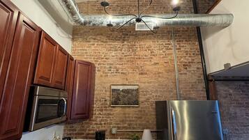 A kitchen with wooden cabinets, a stainless steel refrigerator, a microwave, and a gas stove.