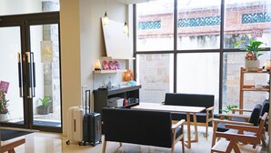A modern hotel lobby with a reception desk, seating area, and large windows.