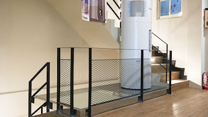 A staircase with a metal railing, a white air purifier, and a small window with a view of the sky.
