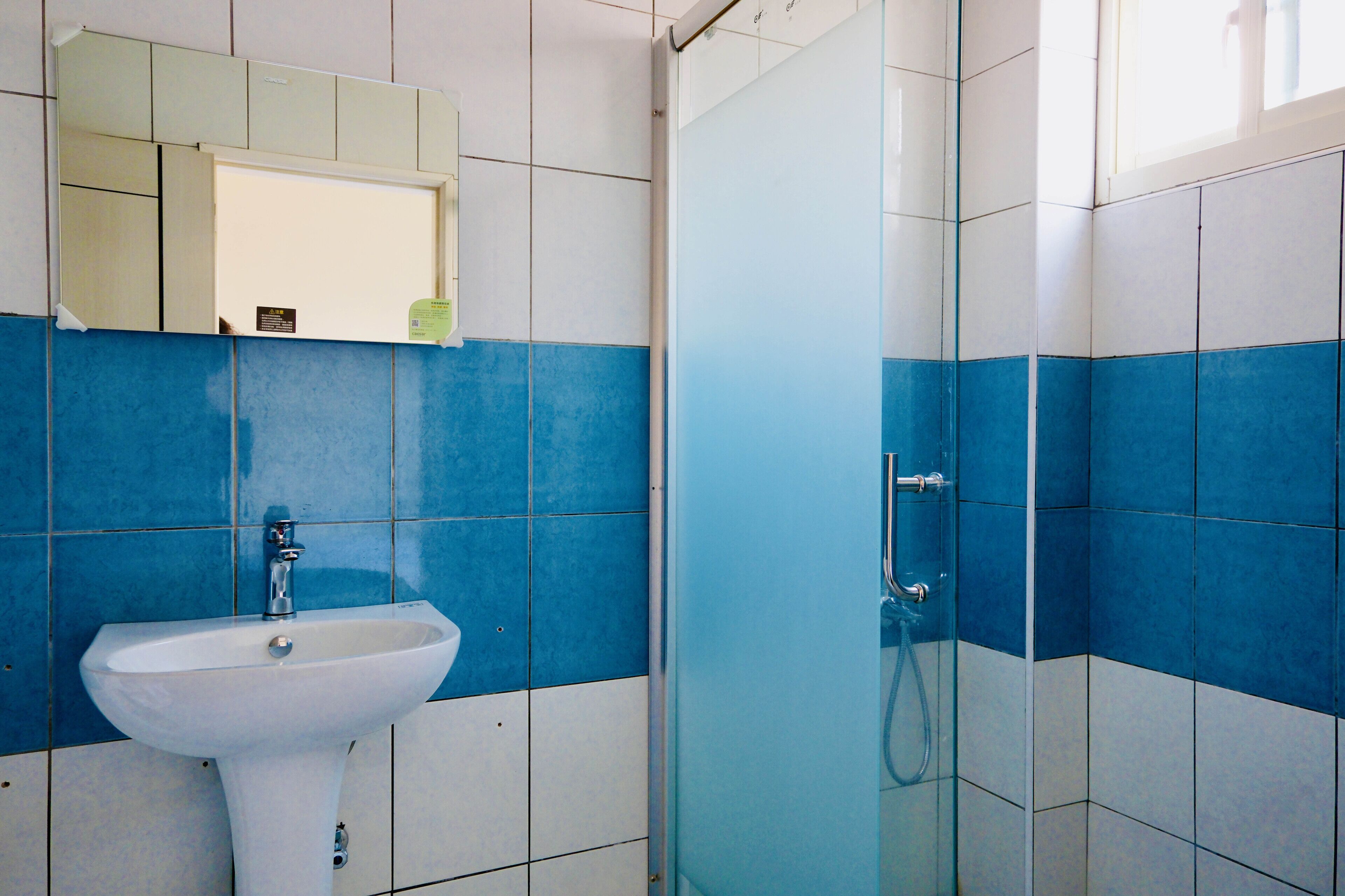 Un baño con un lavamanos blanco, un espejo encima y una cabina de ducha de vidrio.