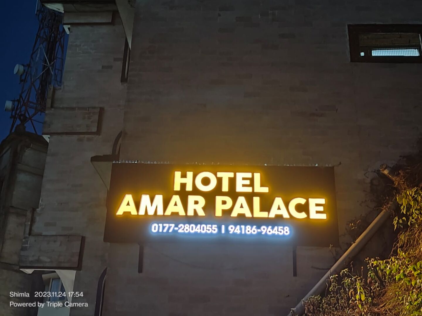 A sign for Hotel Amar Palace with contact numbers.