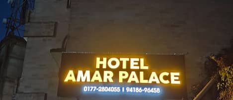 A sign for Hotel Amar Palace with contact numbers.