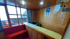 A room with a red cushioned bench, a wooden counter, and a brick wall. - Hotel Amar Palace (Shimla)