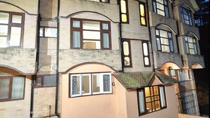 A multi-story building with large windows and a mix of brick and stucco exteriors. - Hotel Amar Palace (Shimla)