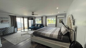 A modern bedroom with a large bed, a sofa, a small table, and a balcony with a view. - 5BR Retreat w/ Salt Water Pool, Spa, Fire Pit &BBQ (San Diego)