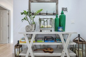 A white wooden console table with a guitar, books, and decorative items.