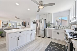 Una cocina moderna con muebles blancos, electrodomésticos de acero inoxidable y una isla central.