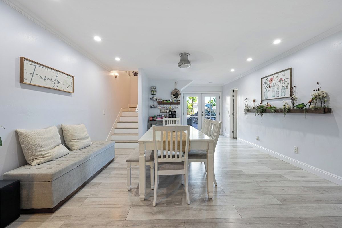 Un interior moderno con comedor, un sofá y una escalera que lleva a otra habitación.