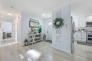 A modern kitchen with white cabinets, stainless steel appliances, and a decorative wreath on the wall.