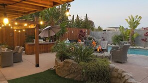 Un patio exterior con zona de bar, asientos y una piscina.