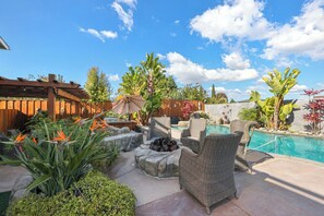 Un patio al aire libre con piscina, mobiliario y diversas plantas.